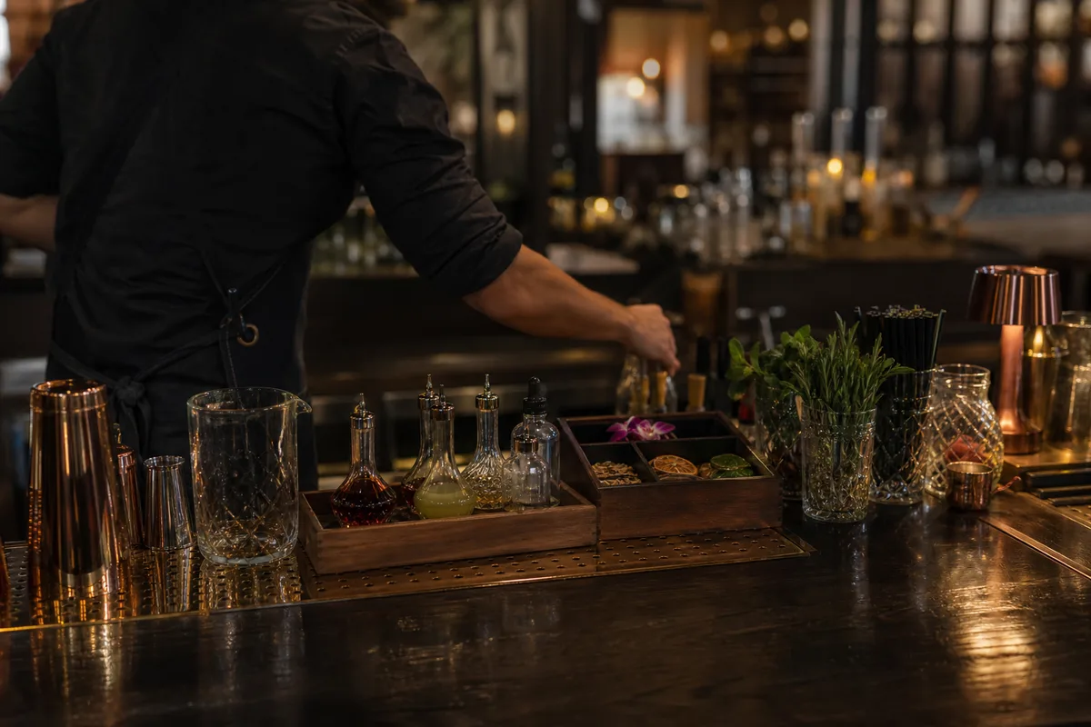 Barman organisant sa mise en place derrière un comptoir de bar à cocktails