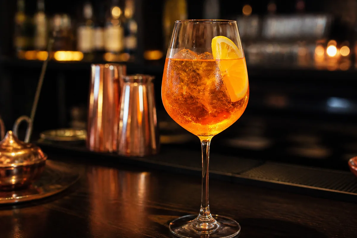 Spritz orangé servi dans un grand verre à vin avec tranche d&rsquo;orange